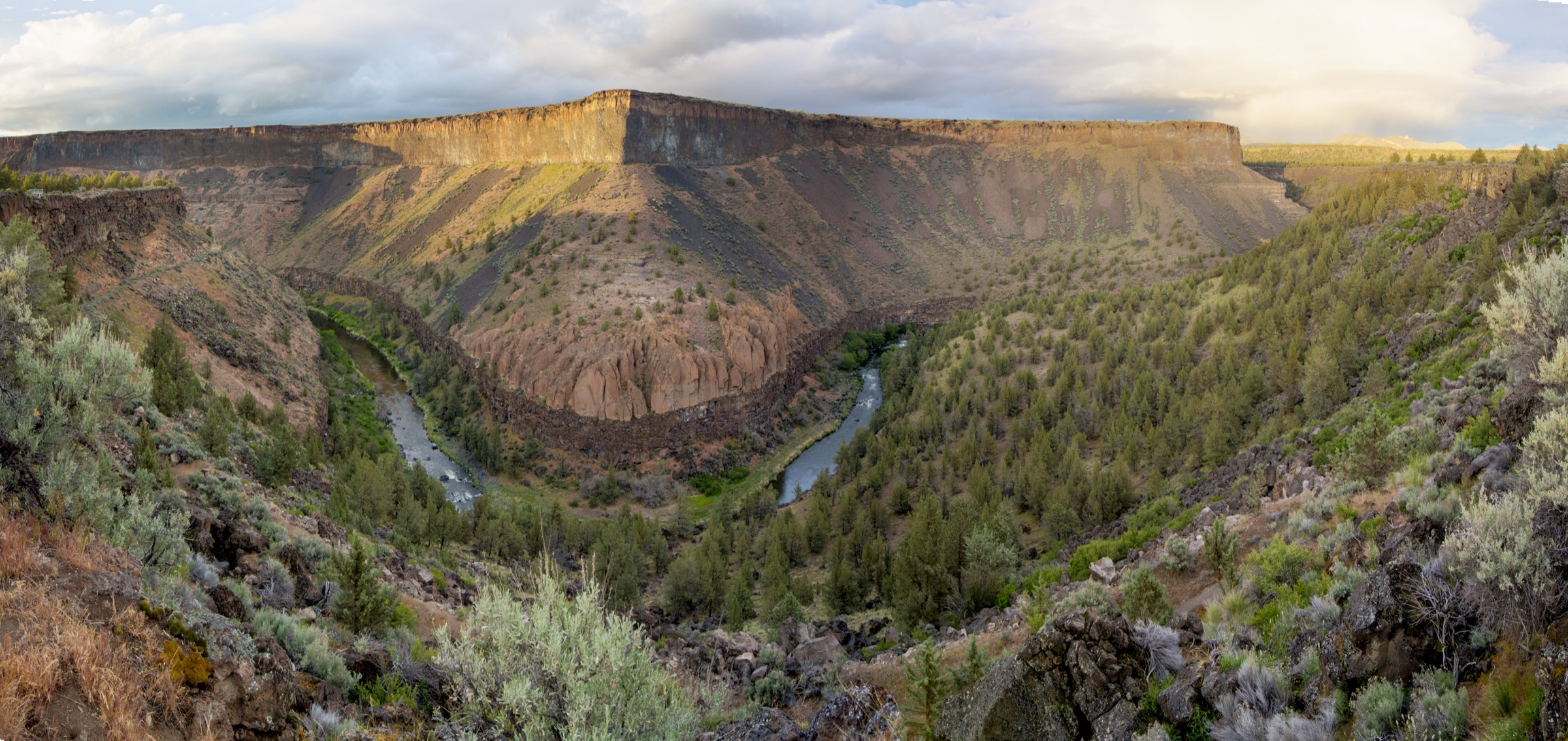 Sunlight across the cliffs and winding water of the Crooked River canyon in Central Oregon.